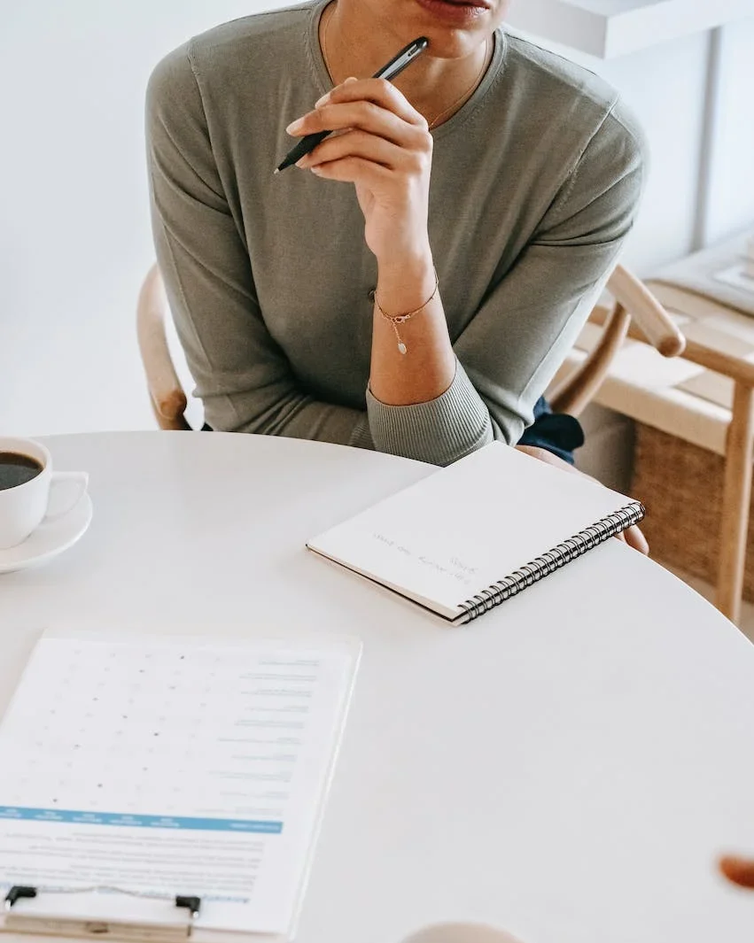 Woman holding a pen with notebook on the table